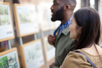 Young couple browsing real estate listings at storefront