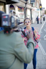 Enthusiastic young woman posing for video camera on urban street