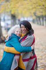 Enthusiastic senior women friends hugging in autumn park