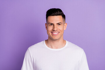 Photo of charming young happy man smile good mood wear white t-shirt isolated on purple color background