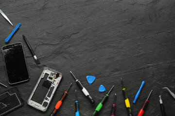 Damaged smartphone and repair tools on black background, flat lay. Space for text