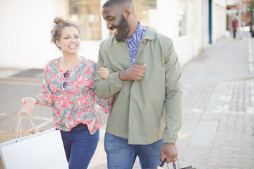 Affectionate young couple with coffee and shopping bag outside storefront