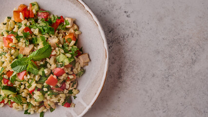 Panoramic view tabbouleh salad. Traditional Middle Eastern or Arabic dish with parsley, mint, bulgur, tomatoes in a bowl on a light background. Top view. Copy space