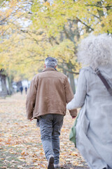 Affectionate couple hugging, walking among trees and leaves in autumn park