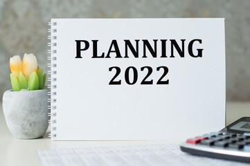 2022 time for a new start. The inscription Planning 2022 on a white notepad on the table. New Year, plans for 2022