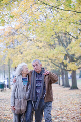 Obraz premium Affectionate couple hugging, walking among trees and leaves in autumn park