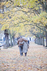 Fototapeta premium Affectionate couple hugging, walking among trees and leaves in autumn park