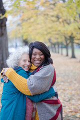 Obraz premium Enthusiastic senior women friends hugging in autumn park