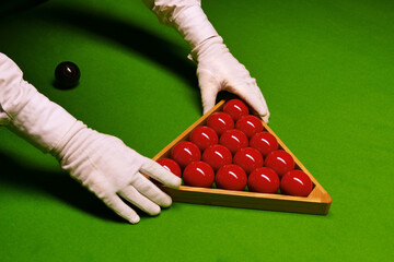 Closeup of the snooker table with the referee arranging the balls.