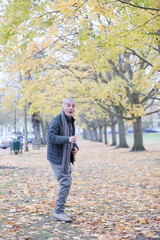 Fototapeta premium Senior man smiling amoung leaves in autumn park