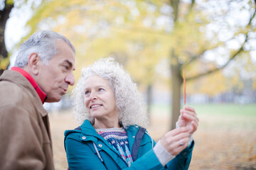 Affectionate senior couple holding orange autumn leaf