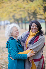 Enthusiastic senior women friends hugging in autumn park