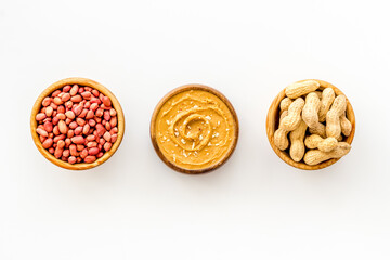 Bowls of homemade peanut butter and nuts on table, top view