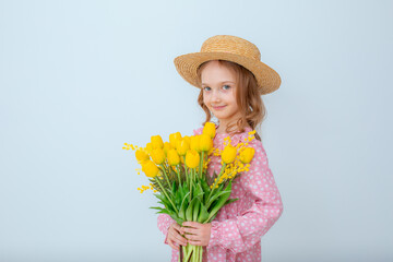 a little girl in a straw hat holds a bouquet of yellow tulips isolated on a white background