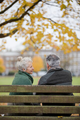 Fototapeta premium Affectionate senior couple talking on bench in autumn park