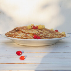 Thin pancakes on plates with fresh strawberries