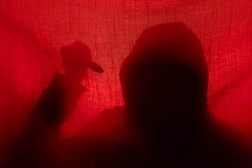 Man with a knife silhouette behind a curtain. Halloween and violence concept