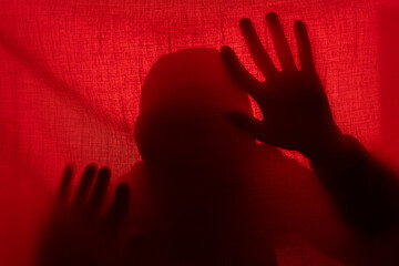 Man silhouette behind a curtain in red light. Halloween and violence concept