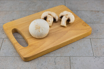 Large size champignon mushrooms placed on a wooden cutting board..