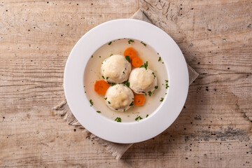 Traditional Jewish matzah ball soup on wooden table	