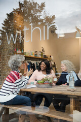 Laughing active senior women friends eating dessert at  cafe