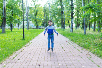 a little boy in a tracksuit jumps up in the park.