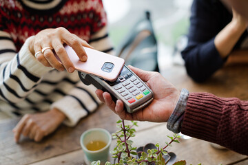 Senior woman paying at cafe with smartphone