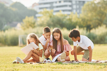 Fototapeta premium Conception of hobbies. Group of happy kids is outdoors on the sportive field at daytime