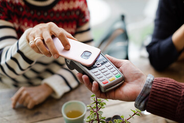 Senior woman paying at cafe with smartphone