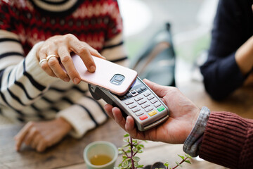 Senior woman paying at cafe with smartphone