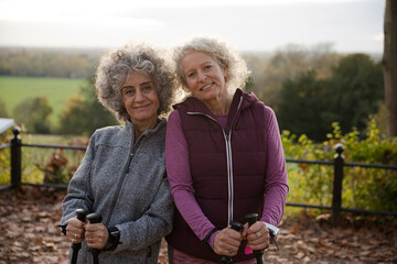 Portrait smiling active senior women friends with walking sticks