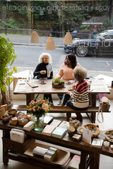 Laughing active senior women friends sharing dessert at autumn park cafe