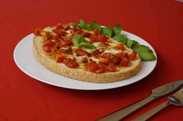 delicious large Italian bruschetta with juicy red tomatoes, mozzarella, garlic, olive oil and fresh basil leaves on a plate	