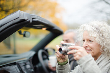 Active senior couple using digital camera in car