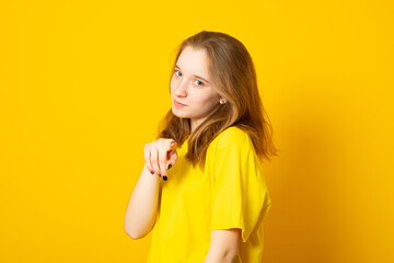 Portrait of a shy girl. Happy smiling teenage girl on a yellow background.