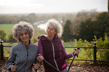 Portrait smiling active senior women friends with walking sticks