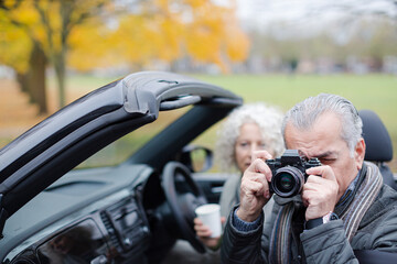 Smiling, affectionate senior couple taking photo from car