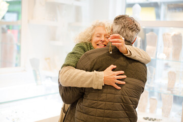 Happy senior woman hugging husband in jewelry store