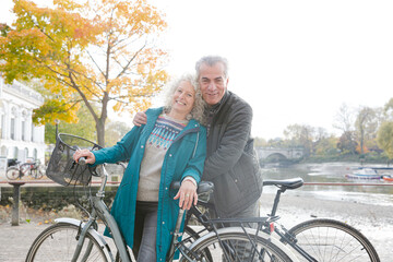 Obraz premium Portrait smiling senior couple bike riding along autumn river