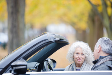 Smiling, affectionate senior couple talking in car