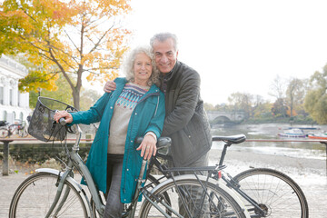 Obraz premium Portrait smiling senior couple bike riding along autumn river