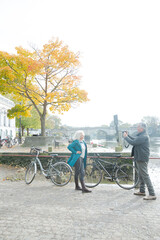 Obraz premium Senior man photographing wife with bicycle in autumn city