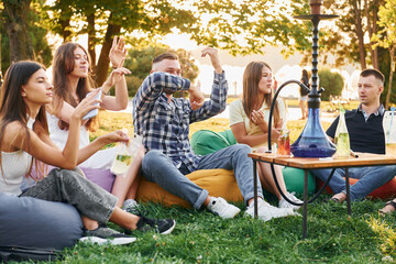 Dancing by the hands. Group of young people have a party in the park at summer daytime