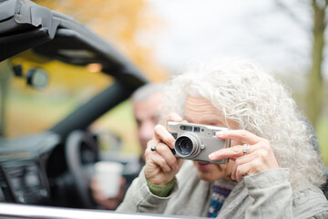 Active senior couple using digital camera in car