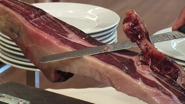 Detail of a man's hand cutting Iberian ham