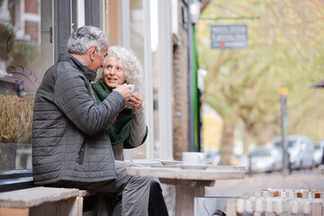 Affectionate senior couple holding hands in autumn cafe