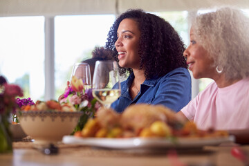 Grandmother With Mother And Granddaughter Enjoying Multi-Generation Family Meal At Home