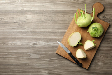Whole and cut kohlrabi plants on wooden table, top view. Space for text - obrazy, fototapety, plakaty