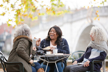 Portrait smiling, happy active senior women friends drinking coffee at autumn park cafe