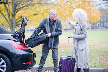 Smiling, affectionate senior couple with 
suitcases